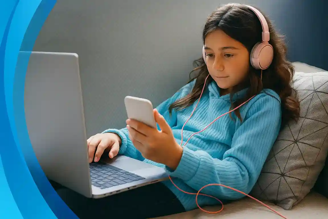 Girl on a couch studying and streaming with headphones on, laptop and phone connected to AT&T Internet.